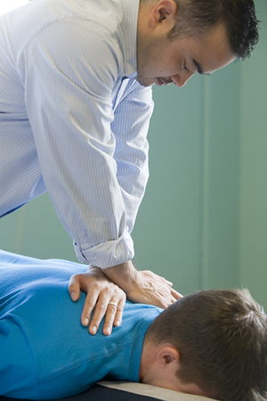 Chiropractor massaging man's back.
