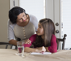 Girl doing homework, talking to woman.