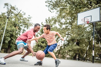 Man and his young son playing basketball as part of a healthy lifestyle to prevent constipation.