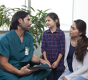 Healthcare provider talking with woman and girl.