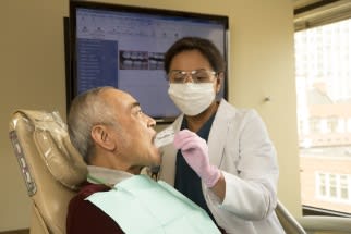 Dental professional working on patient's mouth.