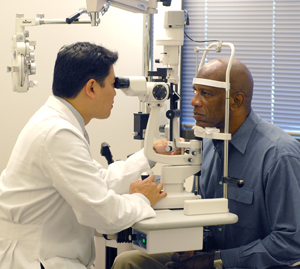 Healthcare provider examining man's eyes with slit lamp.