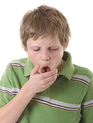 Boy coughing into hand.