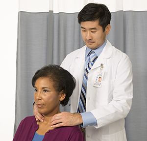 Healthcare provider feeling woman's neck to examine thyroid.