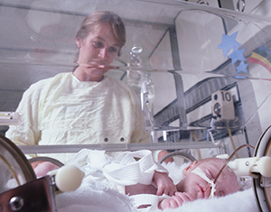 Woman looking at baby in incubator