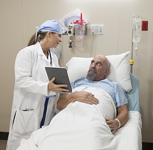 Healthcare provider talking with man in pre-op hospital room