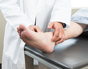 Closeup of healthcare provider examining man's foot.