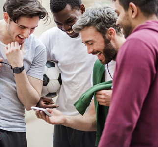 Group of 4 men laughing while looking at a mobile phone