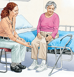 Woman sitting on edge of hospital bed putting on shoe with long-handled grasper. Healthcare provider is sitting next to woman.