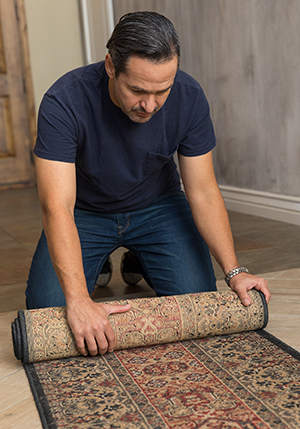 Man rolling up area rug.