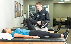 Physical therapist working with woman on leg stretches.