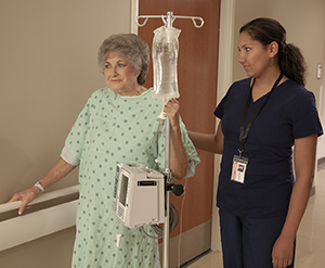 Woman walking in hospital with healthcare provider.