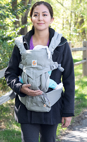 Woman walking outdoors with baby in front carrier.