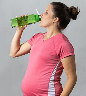 Pregnant woman drinking water after exercise.