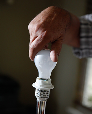 Closeup of man's hands screwing light bulb into lamp.