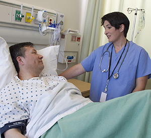 Healthcare provider talking to man in hospital bed.