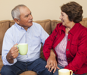 Hombre y mujer mayores sentados en un sofá, hablando.