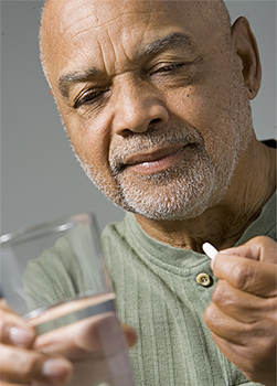 Man about to take a pill with a glass of water.