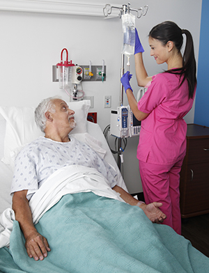 Health care provider checking IV of man in hospital bed.