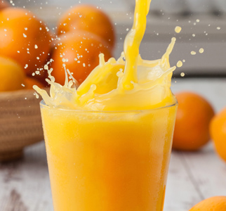 Orange juice splashing into a glass on a table