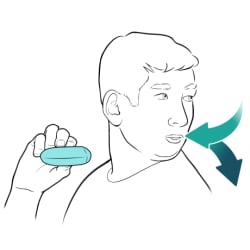 Person holding inhaler, with head turned aside while breathing in and out.